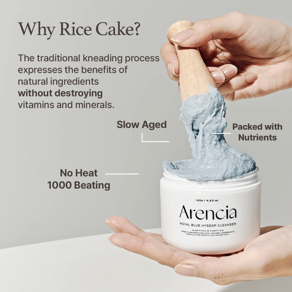 Mano sosteniendo el frasco limpiador "Arencia Royal Blue Hyssop Cleanser" con una cuchara de madera que levanta la pasta limpiadora azul, similar a mochi. El texto en la imagen describe los beneficios del proceso de masa de arroz, como "No Heat", "1000 Beating", "Slow Aged" y "Packed with Nutrients".