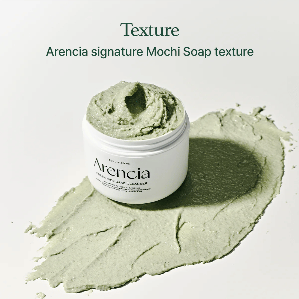 Arencia Fresh Rice Cake Cleanser en tarro abierto con textura cremosa verde similar a mochi extendida alrededor del tarro sobre una superficie blanca.