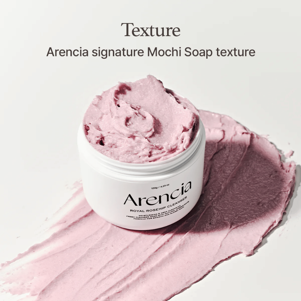 Tarro con Arencia Royal Rosehip Cleanser se ve sobre una limpieza rosa esparcida con textura similar a mochi. El texto arriba describe el producto como la textura característica de Arencia.
