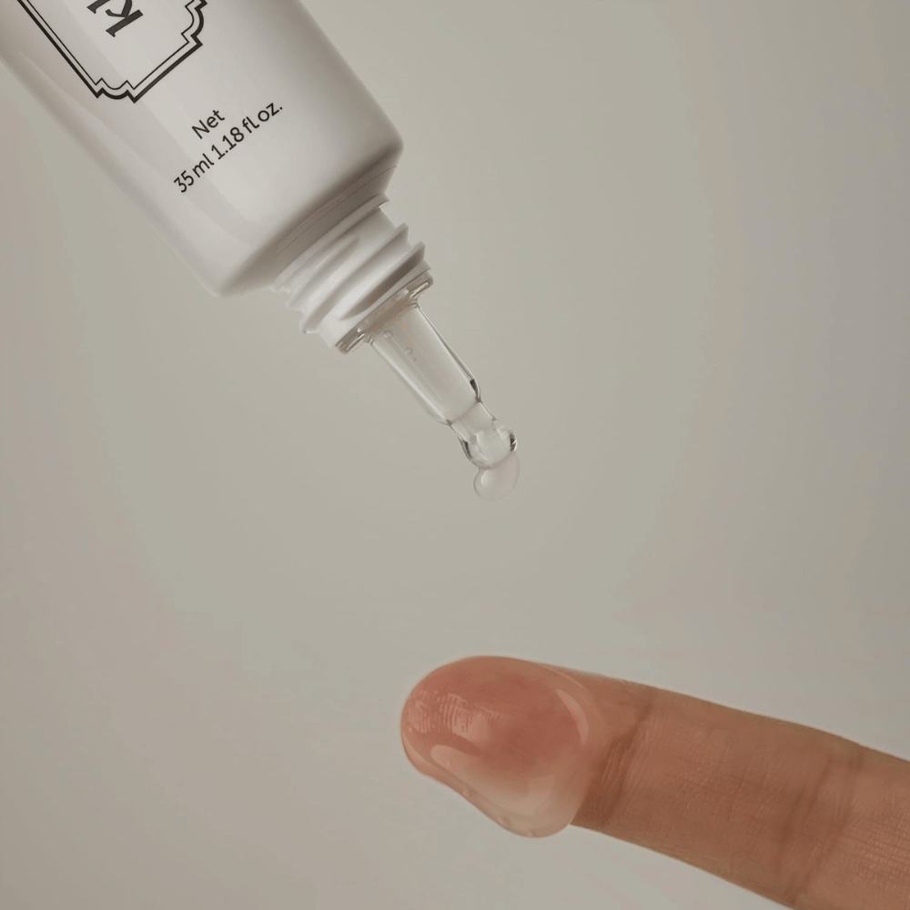 Imagen de detalle en la que un gel claro y ligero se aplica desde la punta estrecha sobre un dedo. La imagen ilustra la consistencia transparente a base de gel del producto y la aplicación precisa alrededor del área de los ojos.