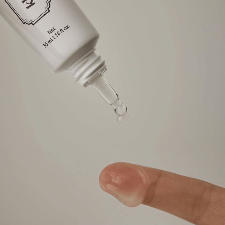 Imagen de detalle en la que un gel claro y ligero se aplica desde la punta estrecha sobre un dedo. La imagen ilustra la consistencia transparente a base de gel del producto y la aplicación precisa alrededor del área de los ojos.