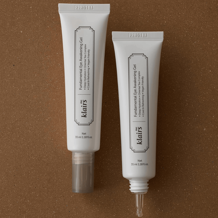 Imagen de producto que muestra Klairs Fundamental Eye Awakening Gel en dos versiones: un tubo cerrado y un tubo abierto que resalta la punta estrecha del aplicador. El envase tiene un diseño blanco minimalista y destaca el enfoque del producto en la hidratación, la sensación refrescante y el cuidado revitalizante del área de los ojos.