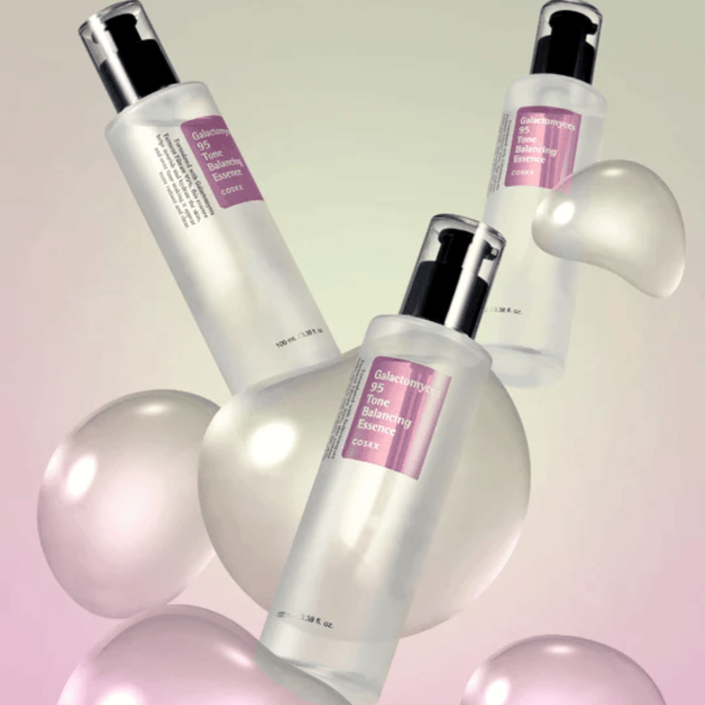 Tres botellas de COSRX Galactomyces 95 Tone Balancing Essence rodeadas de burbujas brillantes. Esencia mejoradora de la piel que unifica el tono de la piel y proporciona un brillo natural.