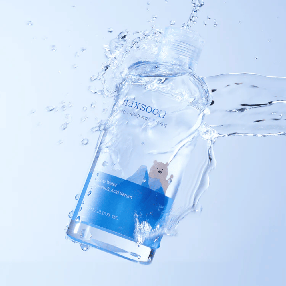 Mixsoon Glacier Water Hyaluronic Acid Serum-botella con etiqueta azul y motivo de oso polar rodeada de agua salpicando contra un fondo azul claro.