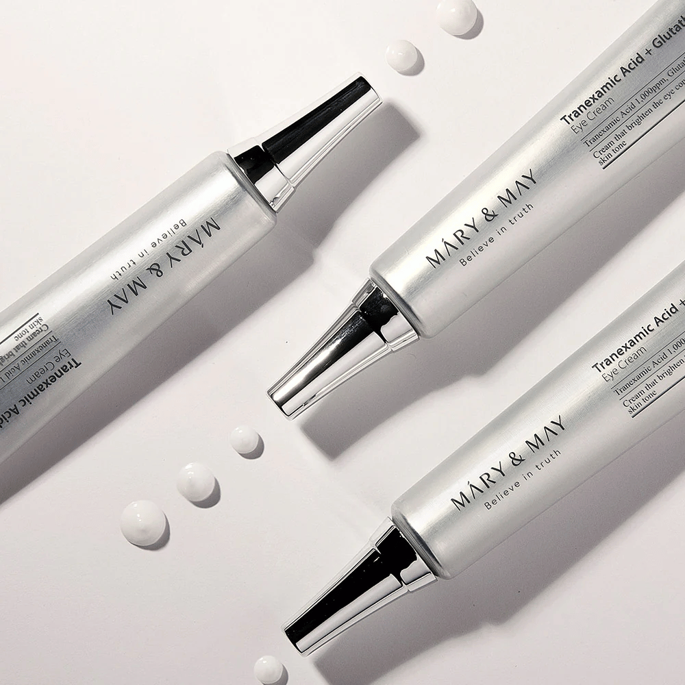 Imagen de producto estilizada de Mary&May Tranexamic Acid + Glutathione Eye Cream que muestra la consistencia de la crema y el enfoque en el cuidado de ojos iluminador.