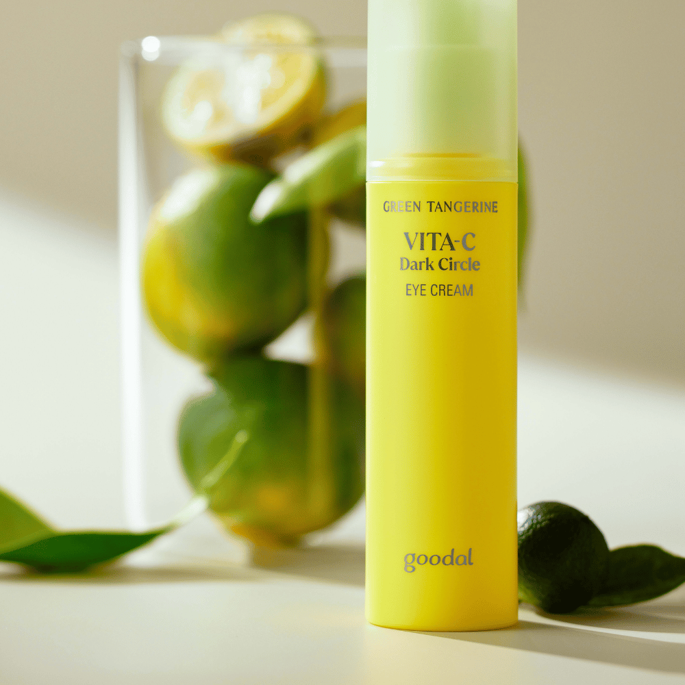 Una botella Goodal Green Tangerine Vita C Dark Circle Eye Cream 30ml sobre una mesa junto a una lima.