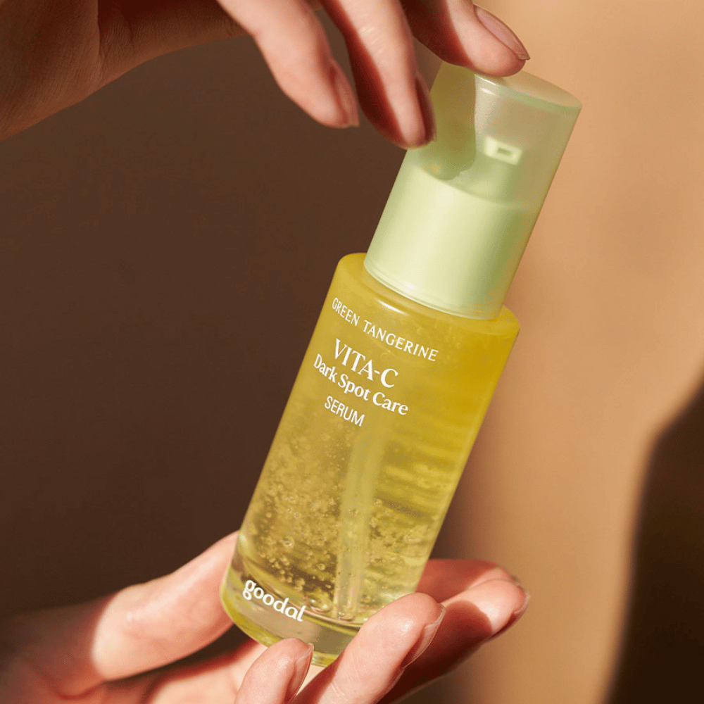 Una persona sosteniendo una botella Green Tangerine Vita C Dark Spot Care Serum de 40ml de Goodal para hiperpigmentación y cuidado de manchas oscuras.
