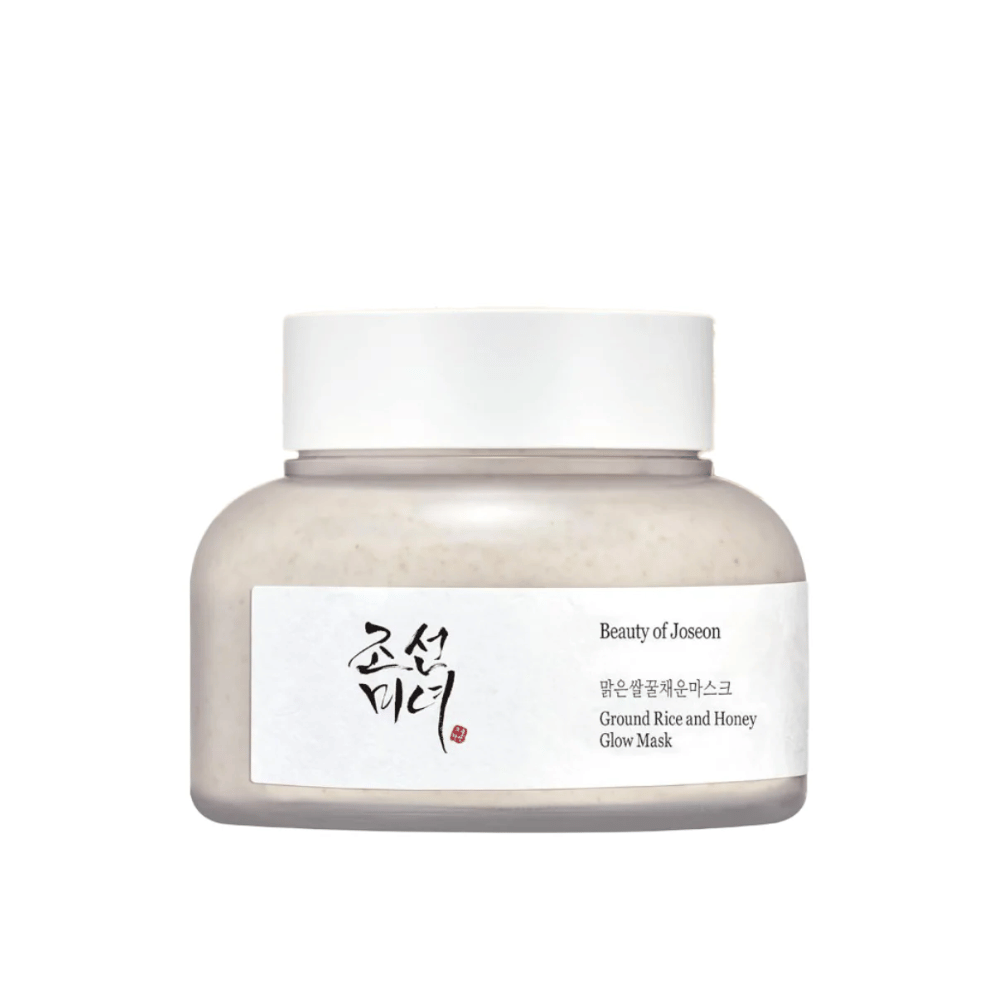Un frasco "Beauty of Joseon Ground Rice and Honey Glow Mask". El empaque es sencillo con una tapa blanca y una etiqueta que presenta el nombre del producto y los ingredientes en coreano e inglés. El producto está diseñado para dar brillo y nutrición a la piel.
