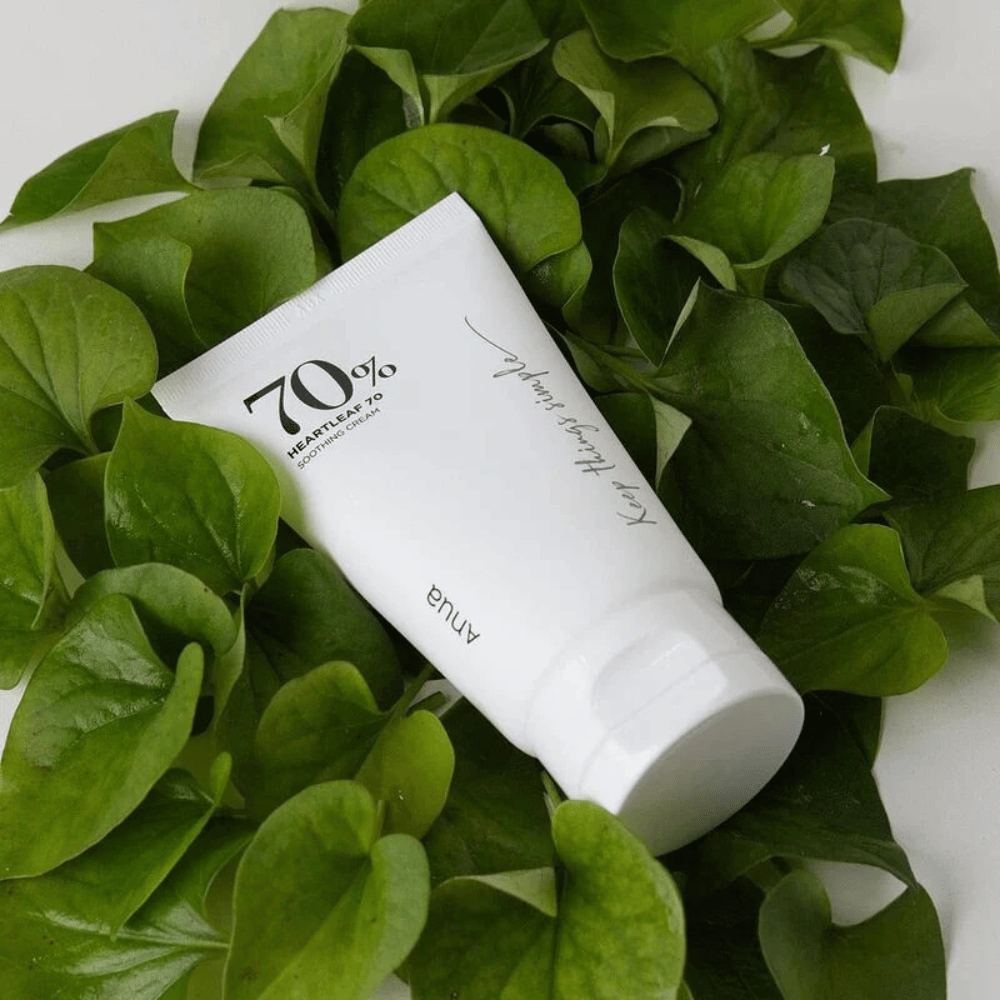 Un tubo de Heartleaf 70% Soothing Cream descansa sobre una cama de hojas verdes.
