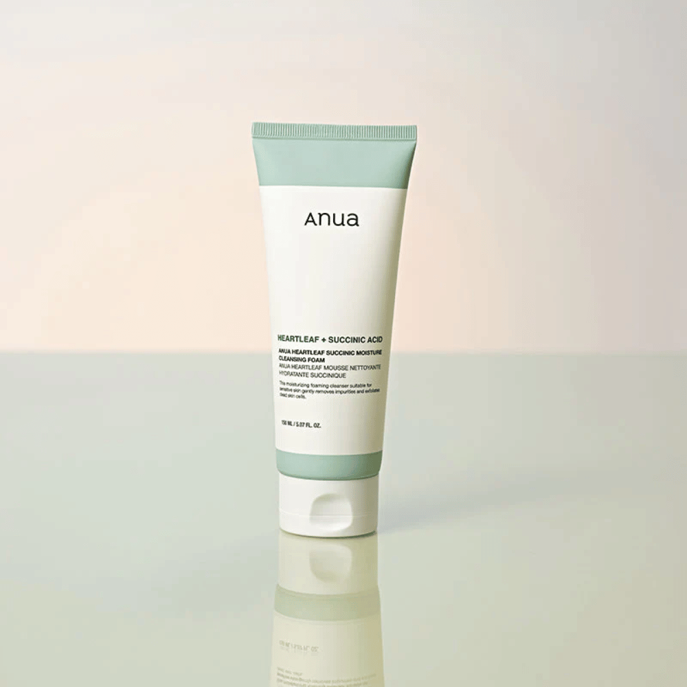 Imagen de producto independiente de Anua Heartleaf + Succinic Acid Moisture Cleansing Foam. El producto se muestra de pie sobre una superficie reflectante que resalta claramente el diseño del envase y la estética elegante de la marca.