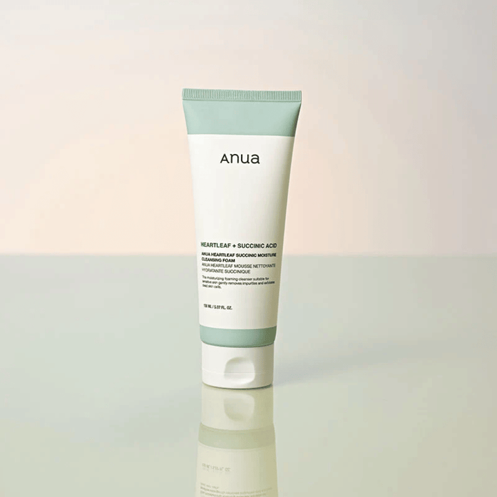 Imagen de producto independiente de Anua Heartleaf + Succinic Acid Moisture Cleansing Foam. El producto se muestra de pie sobre una superficie reflectante que resalta claramente el diseño del envase y la estética elegante de la marca.