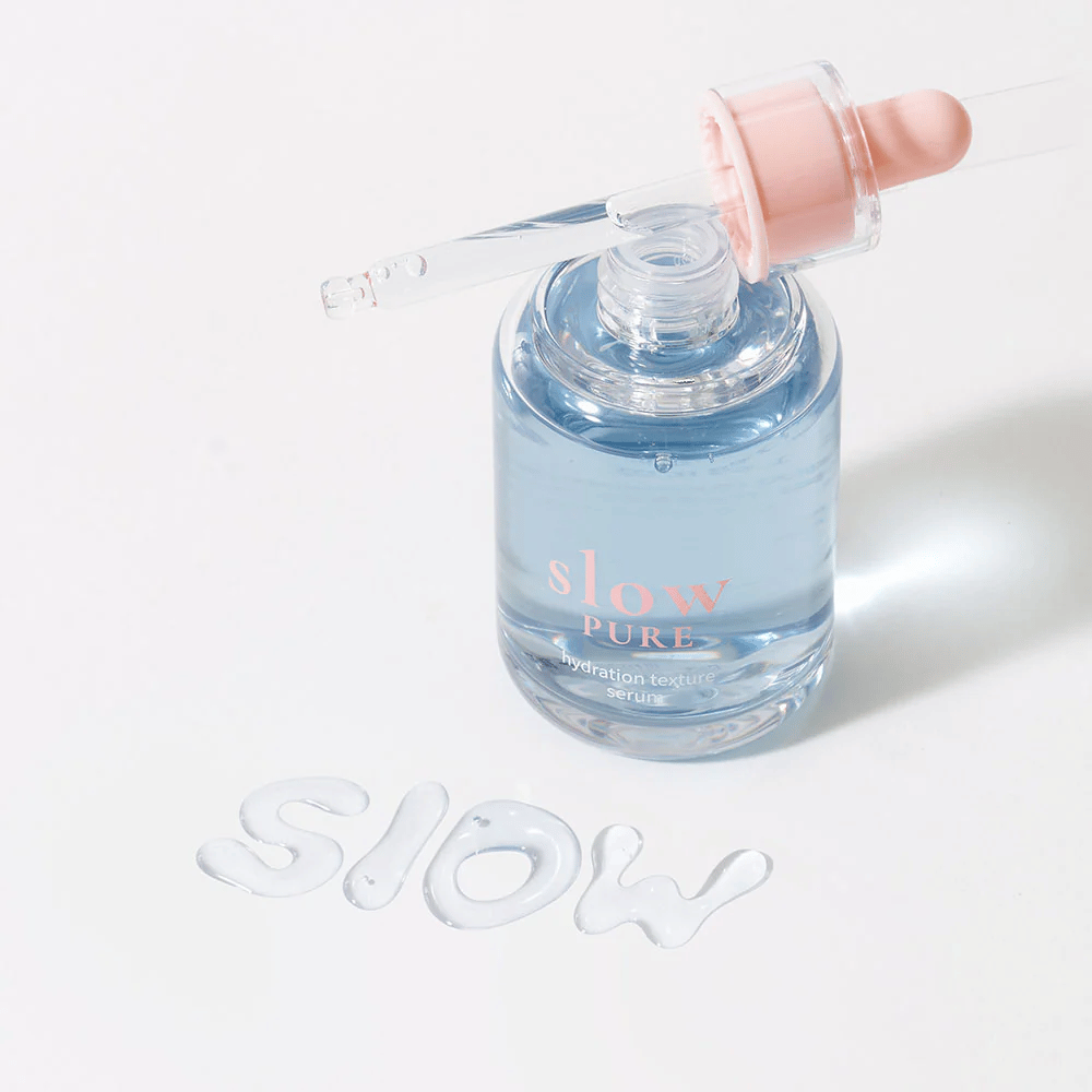 Slow Pure Hydration Texture Serum con pipeta abierta, texto escrito en suero sobre la superficie: "Slow".