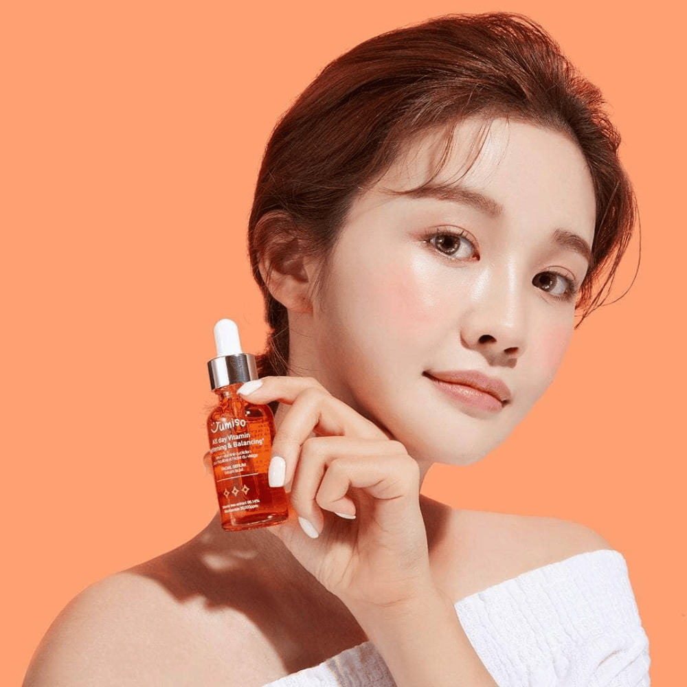 Una mujer sosteniendo una botella de JUMISO All Day Vitamin Brightening & Balancing Facial Serum 30ml.