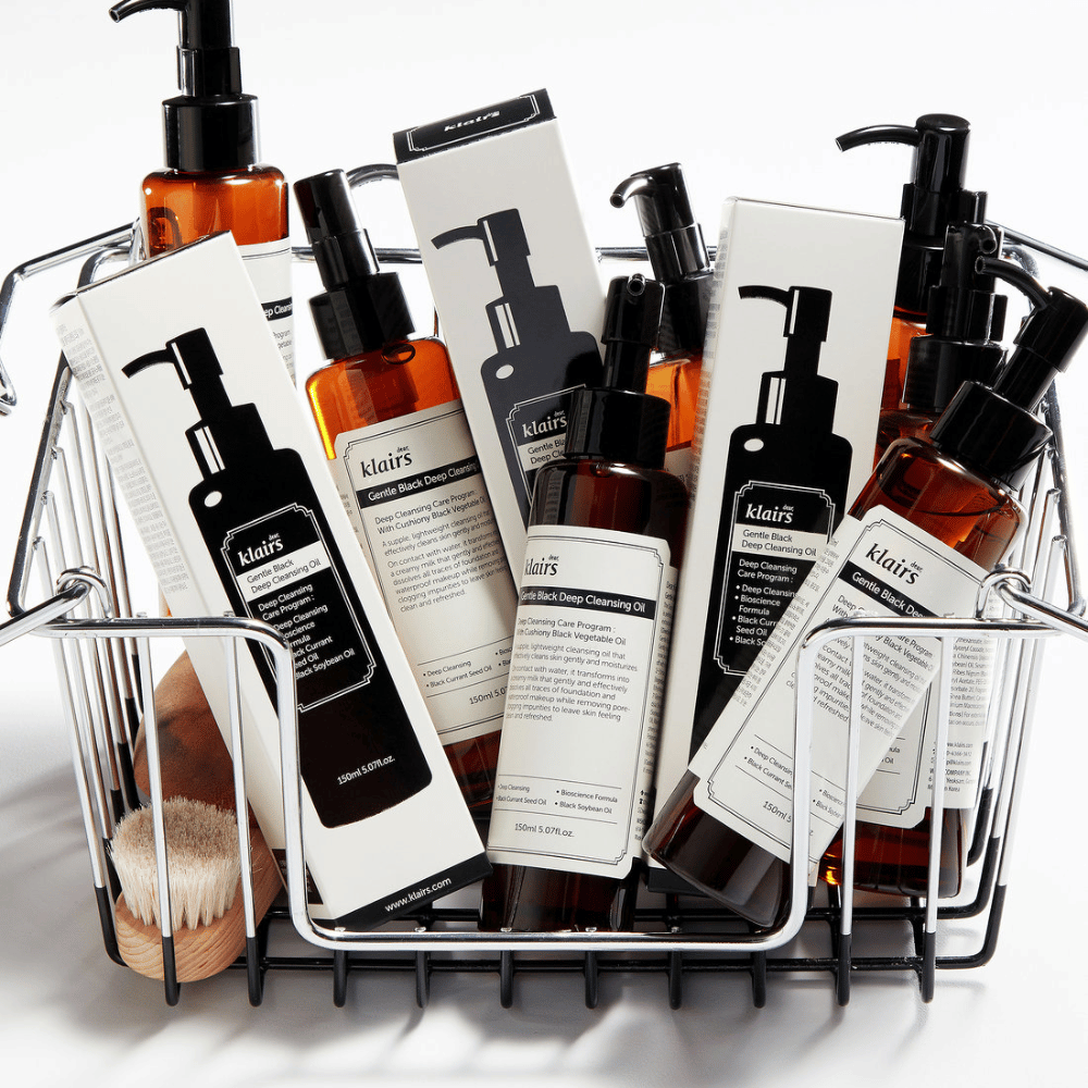 Un mini carrito de compras lleno de productos para el cuidado de la piel de Klairs, incluyendo Gentle Black Deep Cleansing Oil en botellas transparentes con bombas negras y empaques a juego.