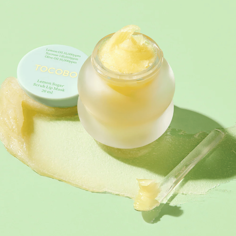 Tarro abierto con Tocobo Lemon Sugar Scrub Lip Mask sobre un fondo verde, con el contenido claramente visible.