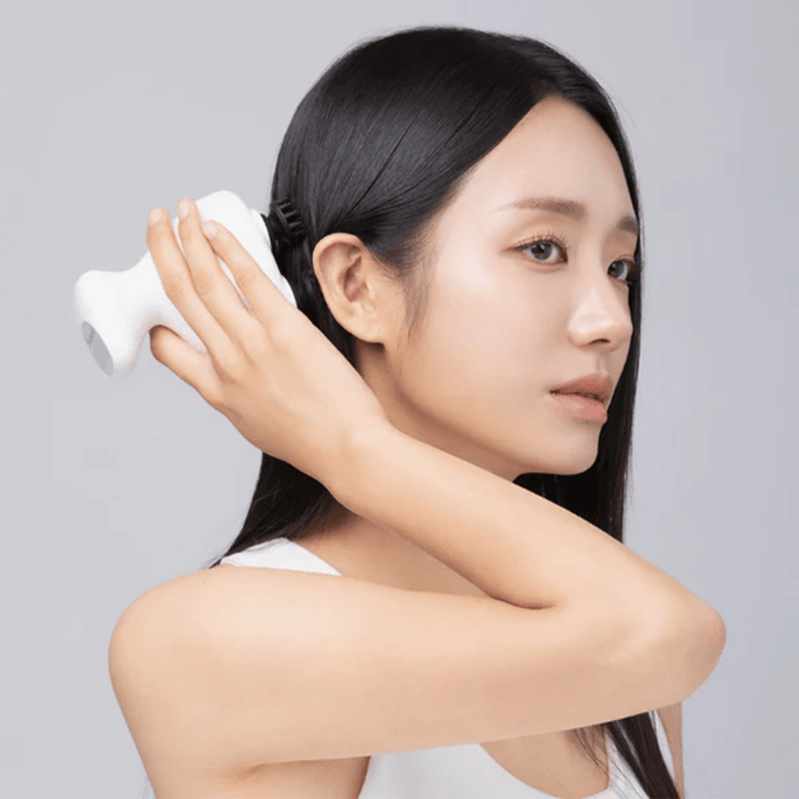 Modelo utiliza Beaund Lift Head Spa directamente sobre el cuero cabelludo detrás de la oreja. La imagen demuestra cómo se utiliza el aparato para masajear el cuero cabelludo y proporcionar una estimulación agradable.