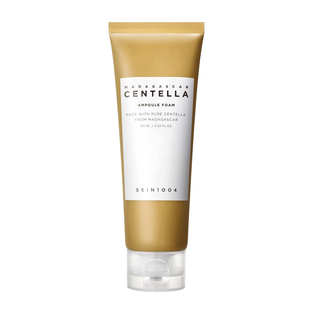 La imagen muestra un tubo de "Madagascar Centella Ampoule Foam" de la marca SKIN1004. Es un producto de limpieza facial que contiene 125 ml / 4.22 fl.oz. La fórmula está basada en Centella pura extraída de plantas en Madagascar. El producto está diseñado para limpiar y cuidar suavemente la piel.