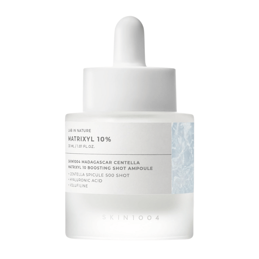 Primer plano de SKIN1004 Madagascar Centella Matrixyl 10 Boosting Shot Ampoule mostrando pipeta y etiqueta – suero de péptidos altamente concentrado para la elasticidad e hidratación de la piel.