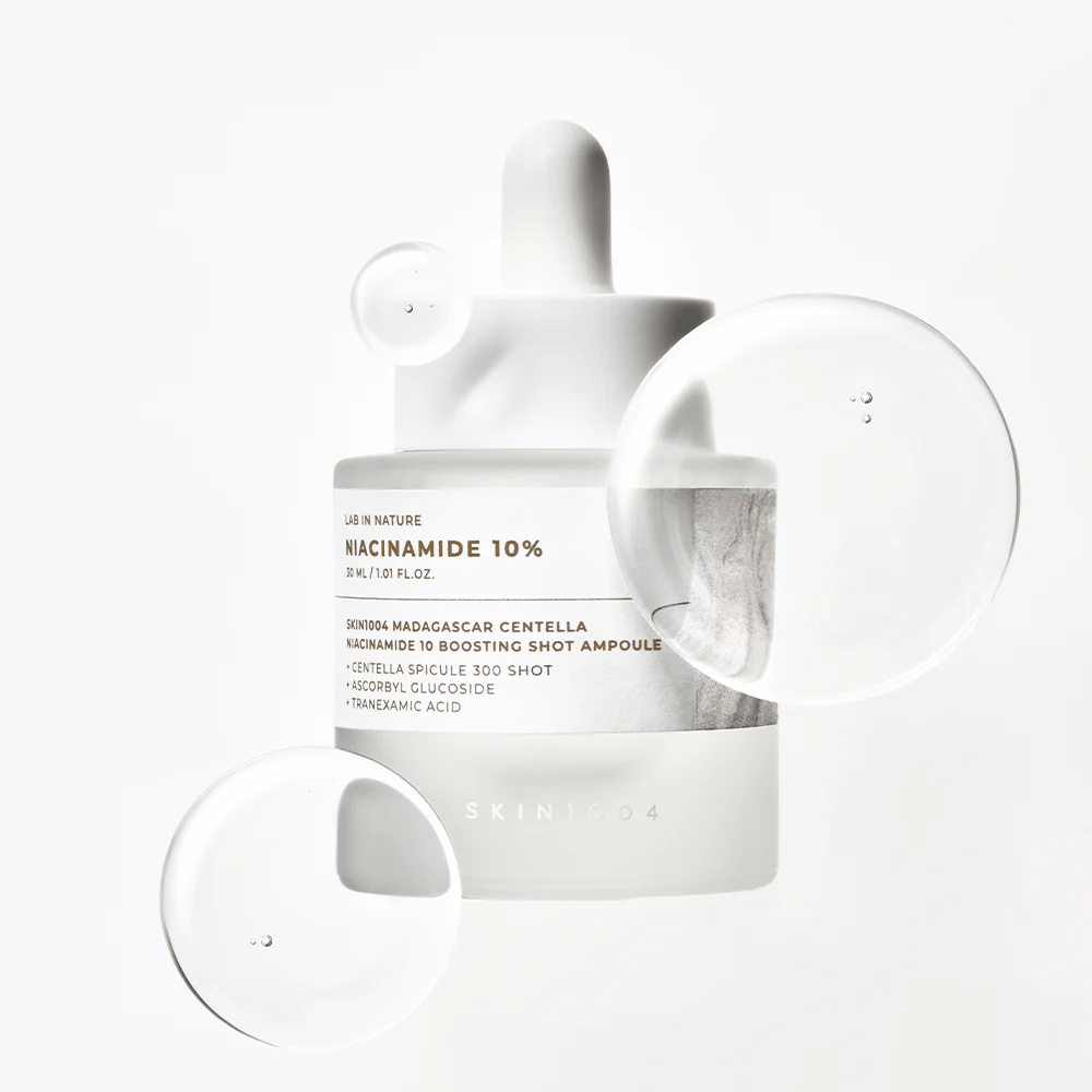 SKIN1004 Madagascar Centella Niacinamide 10 Boosting Shot Ampoule con gotas de suero que muestran una fórmula ligera y de rápida absorción con niacinamida, ácido tranexámico y centella.
