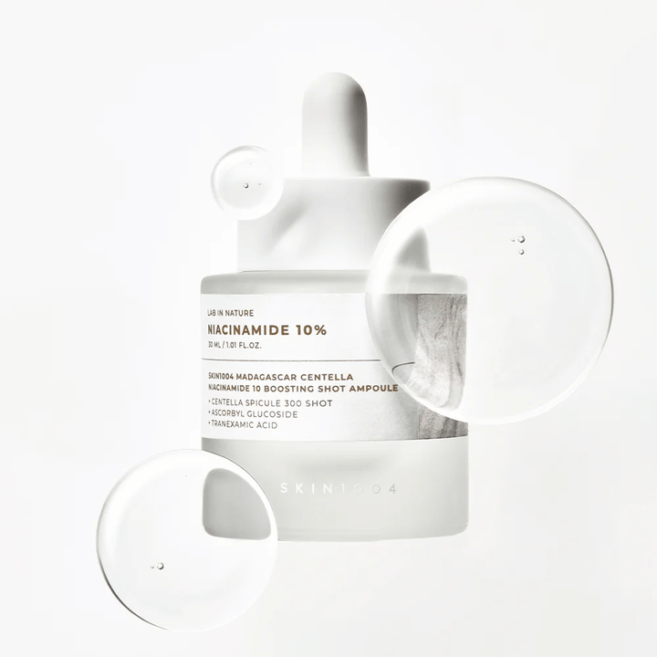 SKIN1004 Madagascar Centella Niacinamide 10 Boosting Shot Ampoule con gotas de suero que muestran una fórmula ligera y de rápida absorción con niacinamida, ácido tranexámico y centella.
