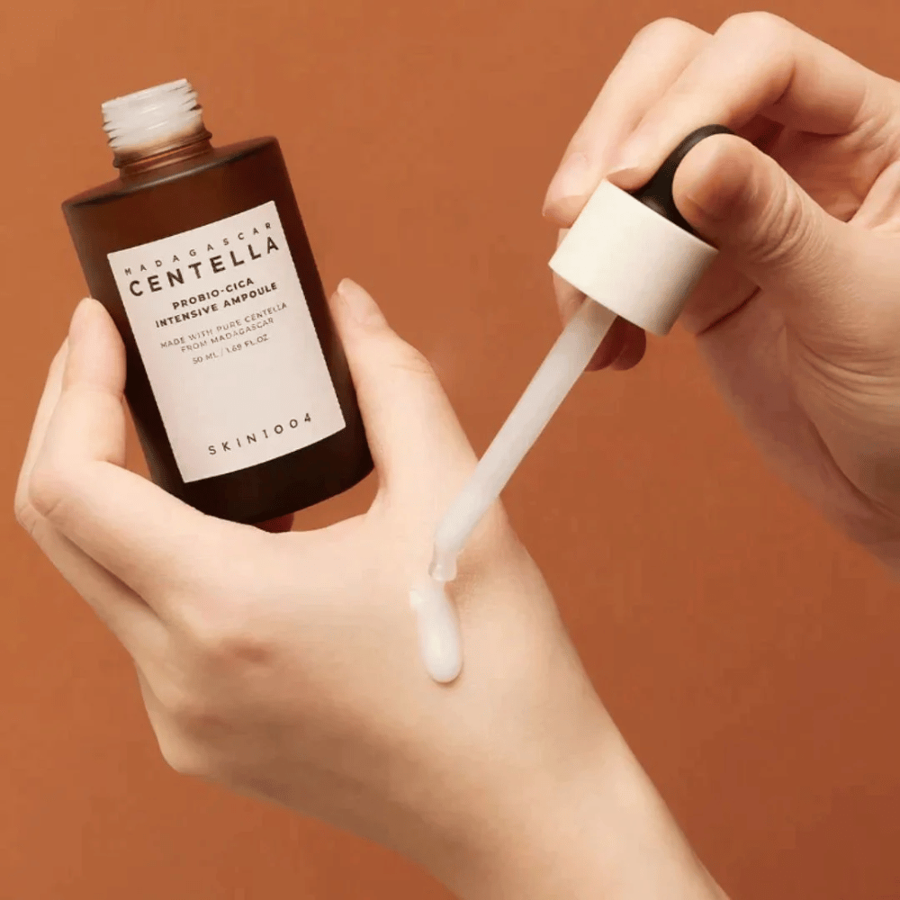Manos usando cuentagotas para dosificar "Madagascar Centella Probio-Cica Intensive Ampoule" de SKIN1004.