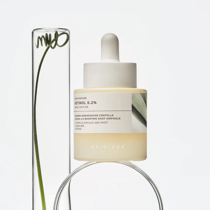 SKIN1004 Madagascar Centella Retinol 0.2 Boosting Shot Ampoule en imagen de estilo de vida con elementos botánicos – suero facial que apoya la renovación de la piel y fortalece la barrera cutánea.