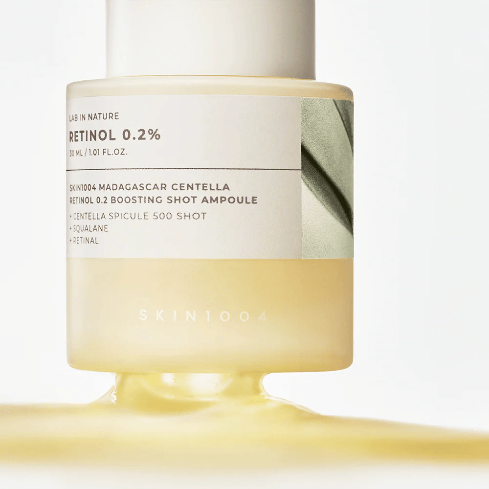 Primer plano de SKIN1004 Madagascar Centella Retinol 0.2 Boosting Shot Ampoule que muestra la consistencia sedosa y amarillenta del suero de retinol para la renovación nocturna de la piel.