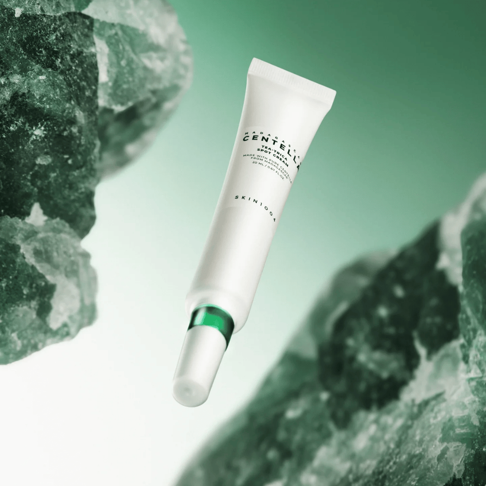 SKIN1004 Madagascar Centella Tea-Trica Spot Cream 20 ml contra acné y granos, imagen del producto con fondo verde y estructura de cristal – calmante spot treatment con centella asiática y tea tree.