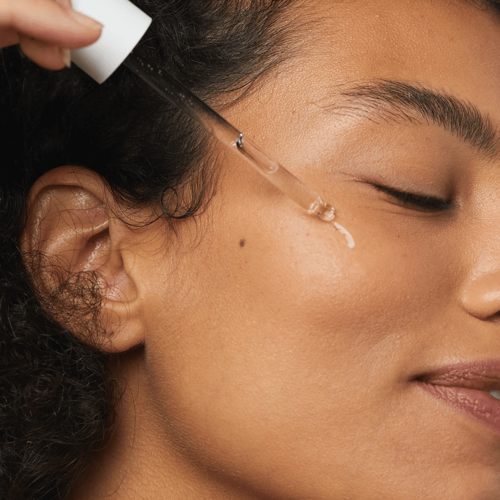 Mujer aplica Skin1004 Madagascar Centella Hyalu-Cica First Ampoule en la mejilla con una pipeta.