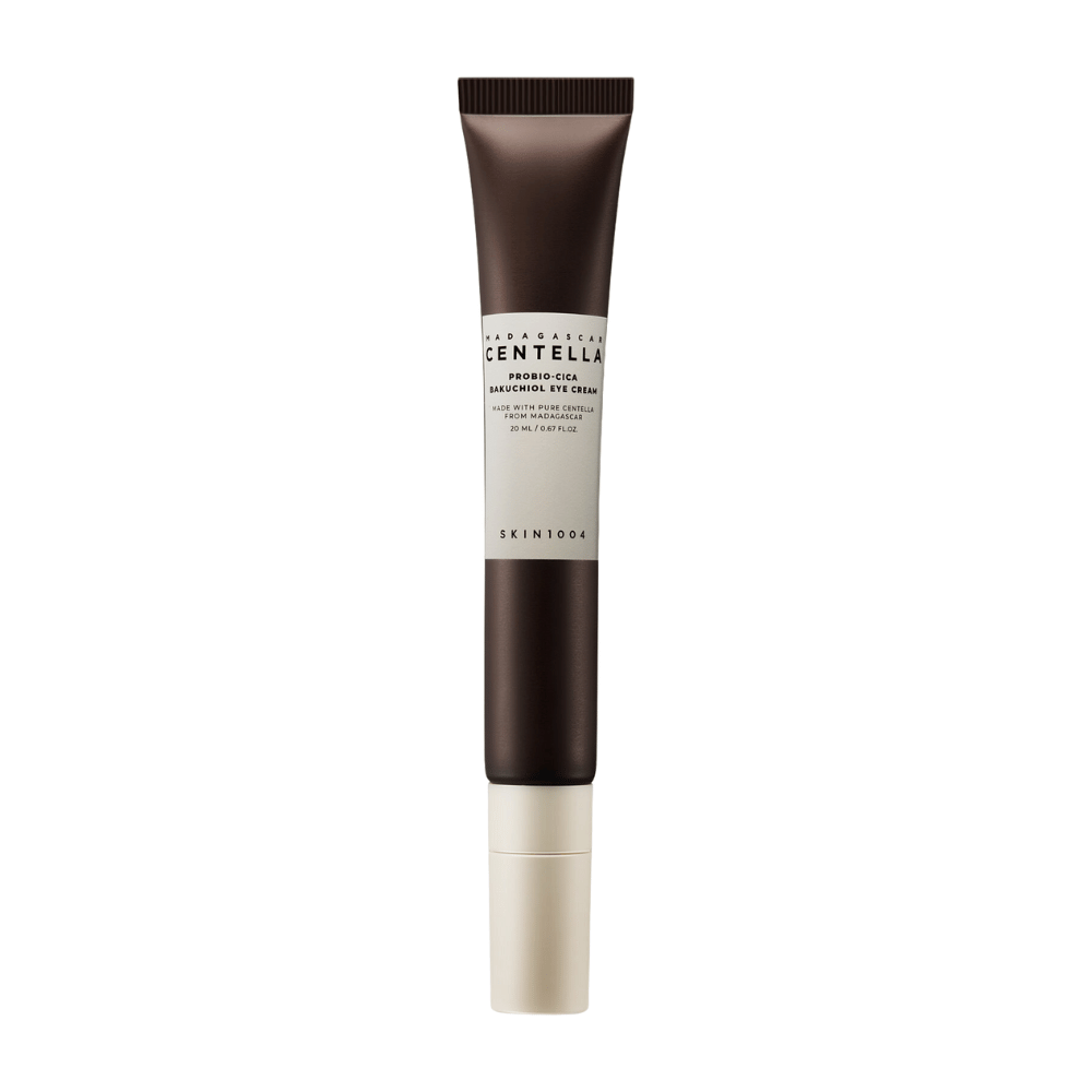 Un tubo de "Madagascar Centella Probio-Cica Bakuchiol Eye Cream" de SKIN1004. El producto está diseñado para el área de los ojos y contiene ingredientes como centella de Madagascar y bakuchiol, conocidos por sus propiedades para el cuidado de la piel e hidratantes. El tubo es elegante con un color marrón oscuro que se desvanece a blanco.