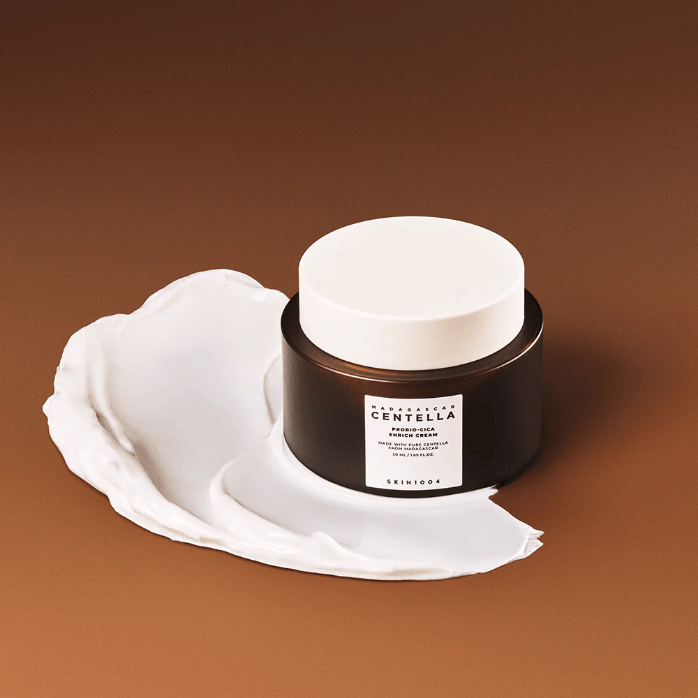 SKIN1004 Madagascar Centella Probio-Cica Enrich Cream colocada sobre una capa de crema - crema facial hidratante y calmante con centella asiática.