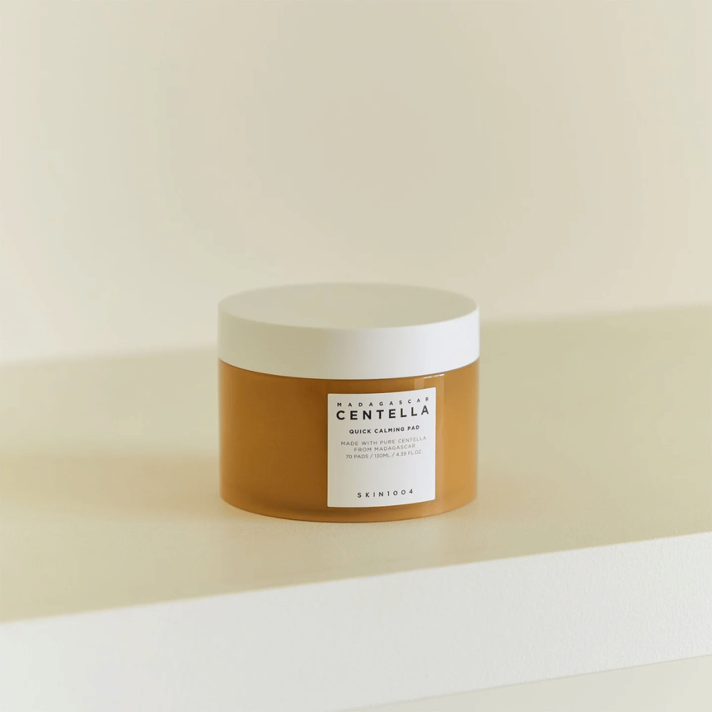 SKIN1004 Madagascar Centella Quick Calming Pad colocada en estante blanco – tarro color ámbar con tapa blanca y etiqueta clara en el frente.
