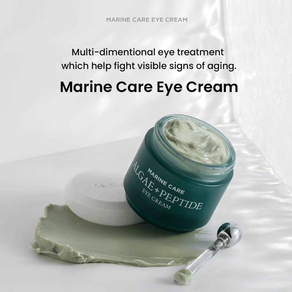 Heimish Marine Care Algae + Peptide Eye Cream en un tarro abierto con crema verdosa. La crema está esparcida al lado del tarro y un aplicador está al lado. El producto combate los signos de envejecimiento y proporciona una hidratación intensa.