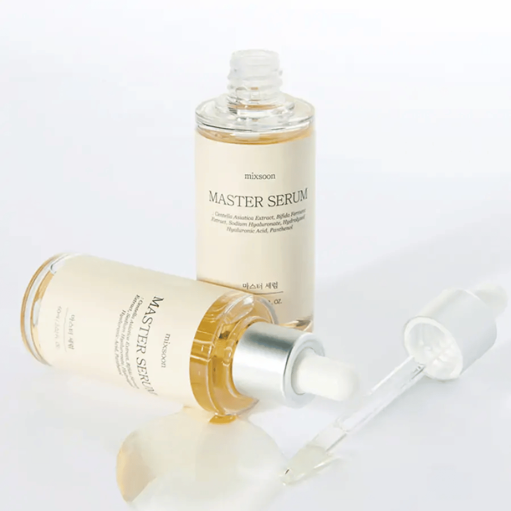 Dos frascos Mixsoon Master Serum, uno de pie y otro acostado con la pipeta abierta, donde el suero se ha derramado sobre una superficie blanca.