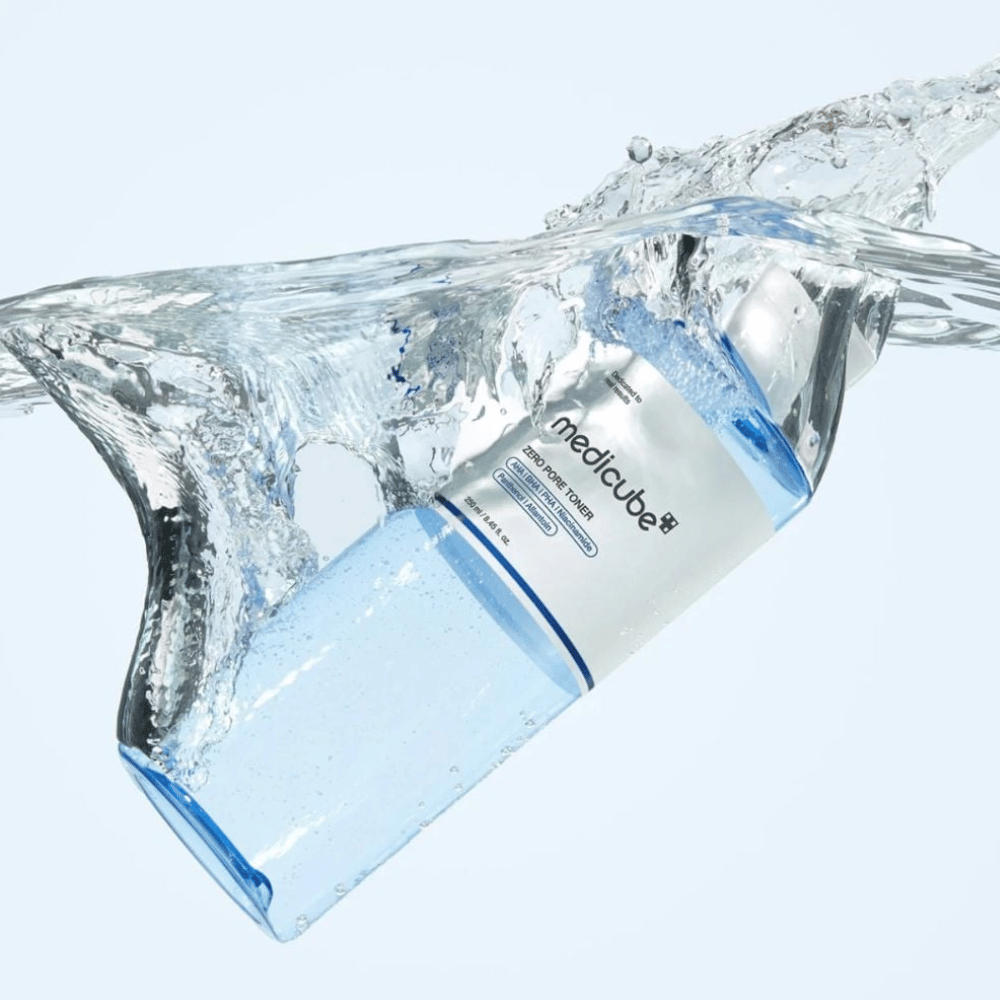Medicube Zero Pore Toner 250 ml, tónico exfoliante con AHA, BHA y PHA. Botella azul transparente rodeada de una gran salpicadura de agua.