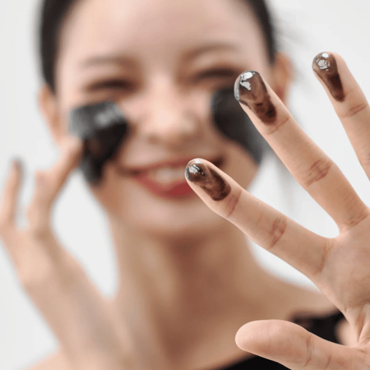 Modelo aplica Cómo Midnight Soothing Cleansing Balm en la piel. Bálsamo limpiador cremoso que limpia en profundidad y deja la piel suave y equilibrada.