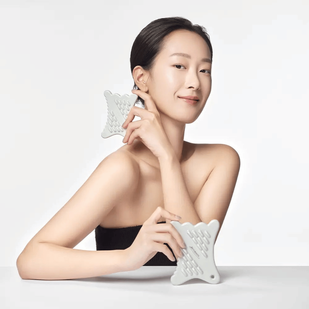 Modelo usando RETURNITY Mini Guasha a lo largo de la línea de la mandíbula para masaje facial y rutina de cuidado de la piel.
