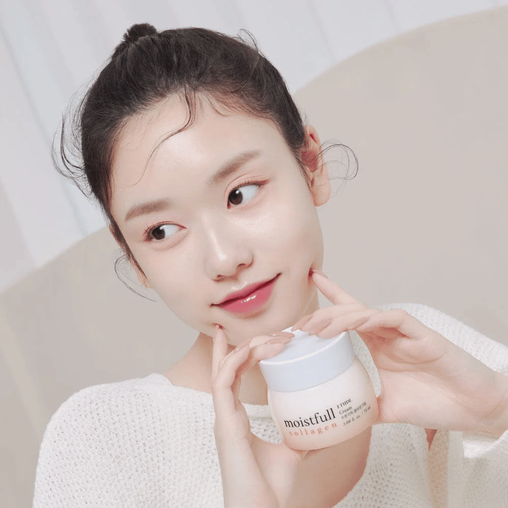 Mujer sostiene un frasco "Moistfull Collagen Cream", camiseta blanca, sonriendo.