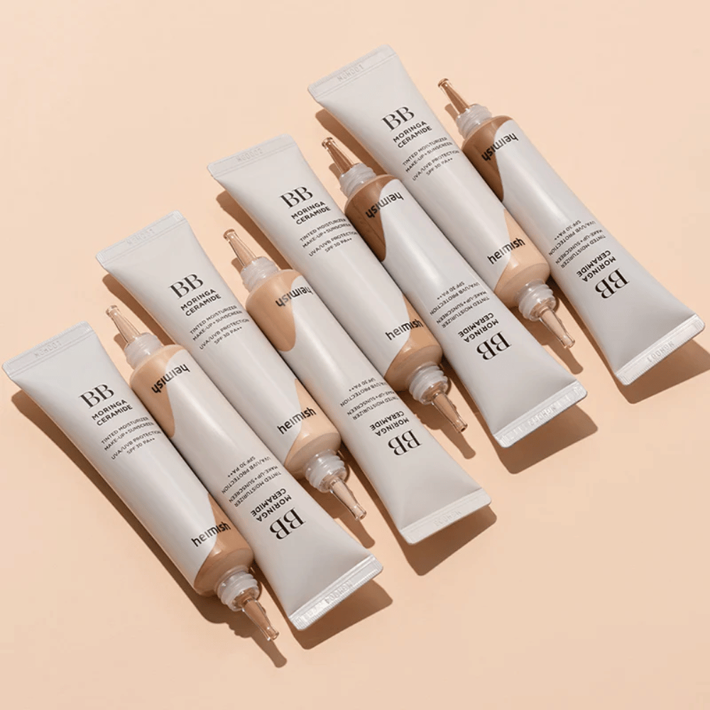 Varios tubos de Heimish Moringa Ceramide BB Cream colocados sobre un fondo beige claro. La imagen resalta los diferentes tonos y el elegante diseño de empaque minimalista del producto.