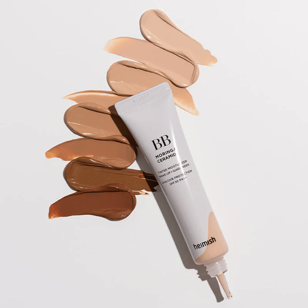 Heimish Moringa Ceramide BB Cream rodeado de varias muestras de tono en diferentes tonos de piel. La imagen muestra la amplia gama de colores del producto y la textura cremosa que proporciona una cobertura natural y un tono de piel uniforme.