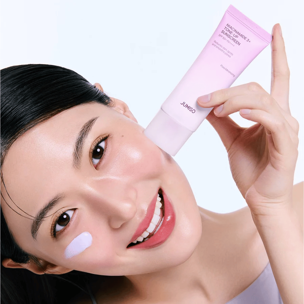 La modelo aplica JUMISO Niacinamide 3+ Tone-Up Sunscreen SPF50+ PA++++ para protección UV, un tono de piel más uniforme y luminosidad natural.