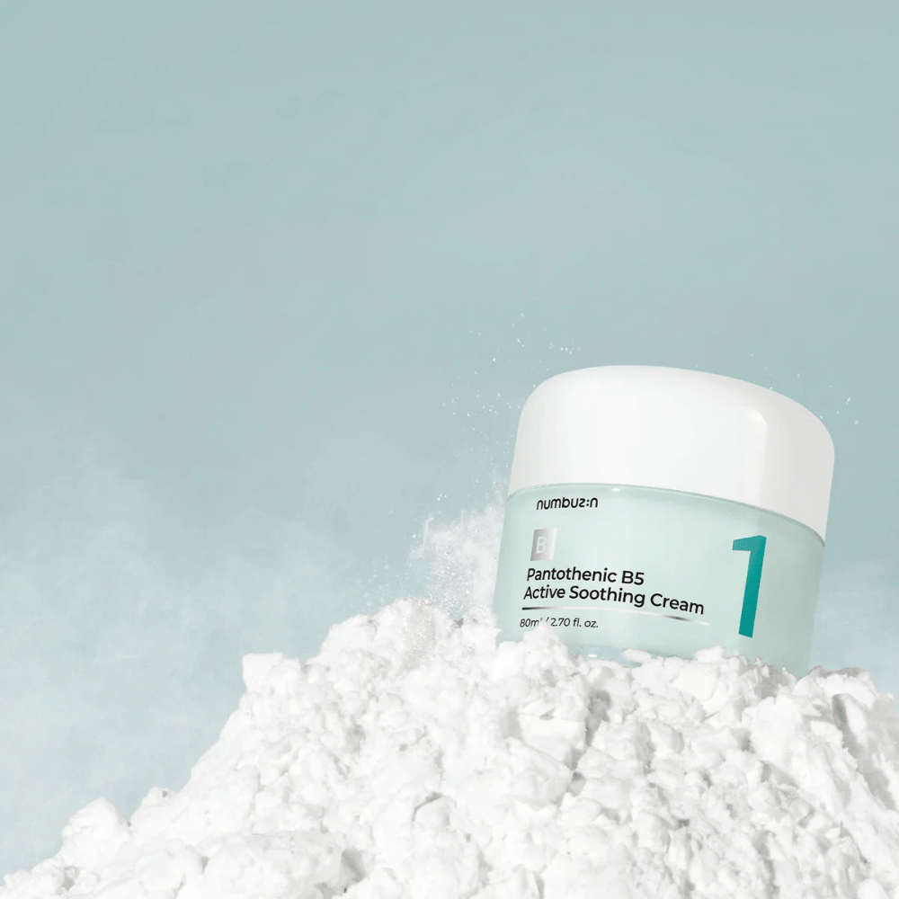 Numbuzin No.1 Pantothenic B5 Active Soothing Cream 80 ml en un frasco verde claro con tapa blanca, colocado sobre una pila de polvo blanco contra un fondo claro.
