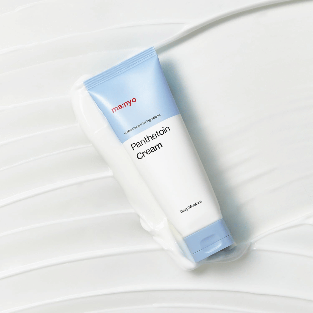 2. Ma:nyo Panthetoin Cream – crema facial hidratante en tubo blanco y azul claro rodeado de textura cremosa sobre fondo blanco