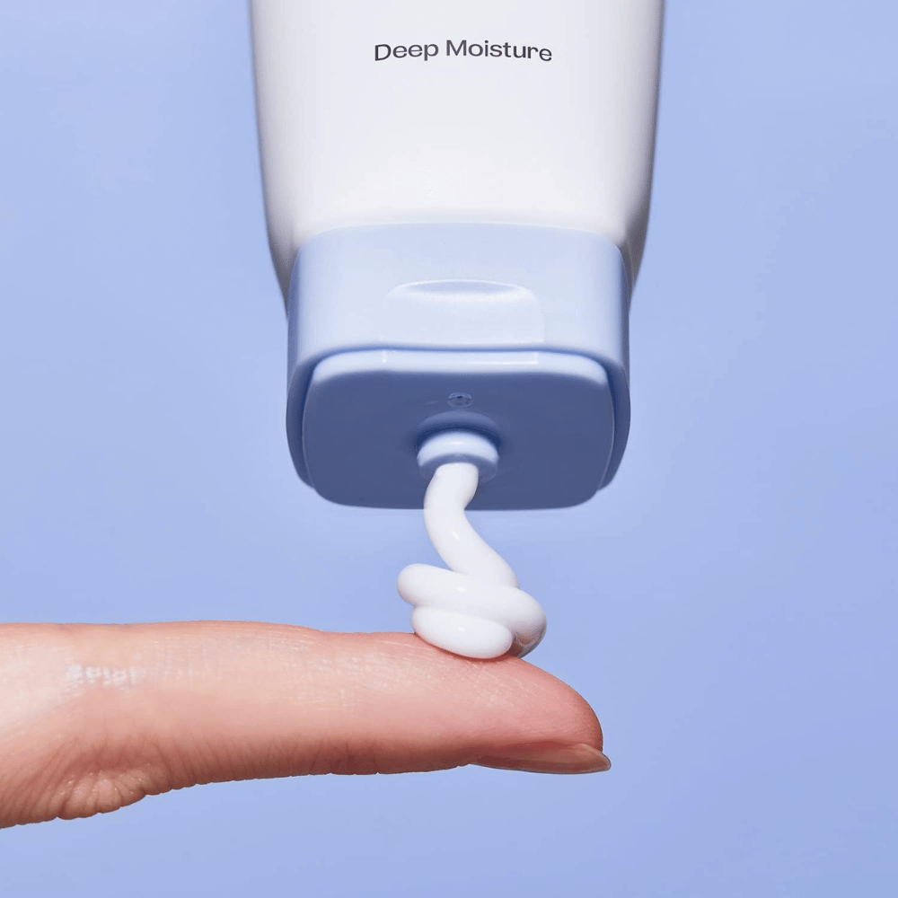 1. Ma:nyo Panthetoin Cream – primer plano de crema facial hidratante blanca aplicada desde un tubo azul claro sobre un dedo