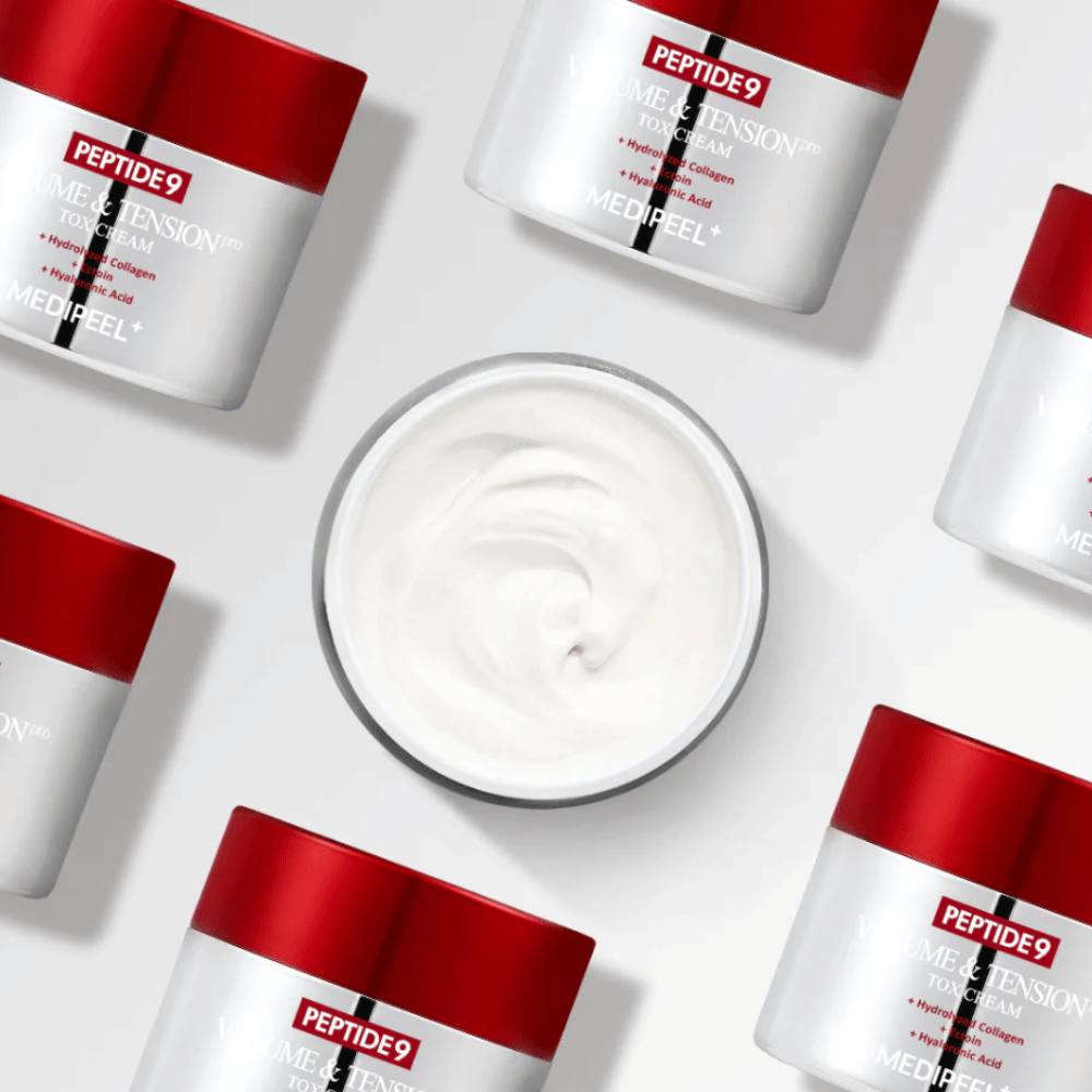 Varios tarros de MEDI-PEEL Peptide 9 Volume & Tension Tox Cream dispuestos sobre un fondo blanco. El producto hidrata intensamente y aporta volumen y luminosidad a la piel.