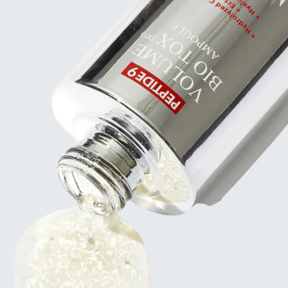 Primer plano de MEDI-PEEL Peptide 9 Volume Bio Tox Pro Ampoule siendo vertido. La fórmula clara con colágeno, ectoína y ácido hialurónico hidrata profundamente.