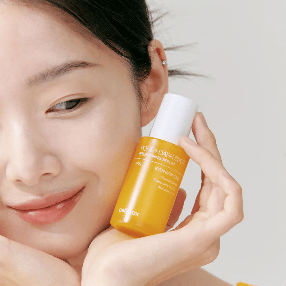 Modelo sostiene Celimax Pore + Dark Spot Brightening Serum cerca de la cara, mostrando una piel radiante.