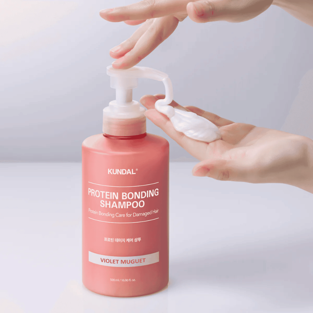 La mano bombea KUNDAL Protein Bonding Shampoo Violet Muguet en una consistencia cremosa, champú reparador para cabello dañado.