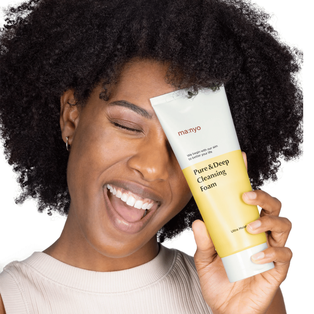 Mujer con cabello rizado sostiene Ma:nyo Pure & Deep Cleansing Foam - un limpiador coreano suave que elimina eficazmente la suciedad y el maquillaje sin resecar la piel.