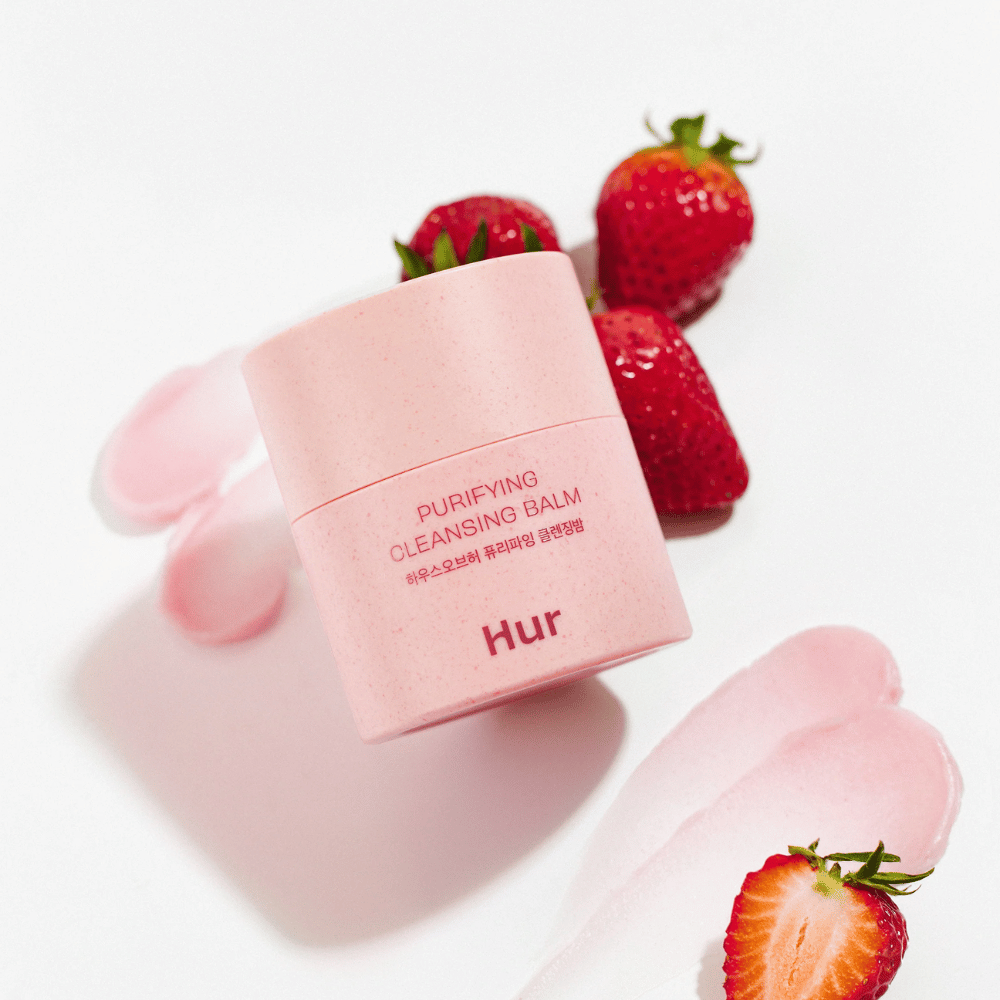 Cómo Purifying Cleansing Balm colocado con fresas frescas. Bálsamo limpiador que deja la piel suave y es adecuado para la limpieza facial diaria.